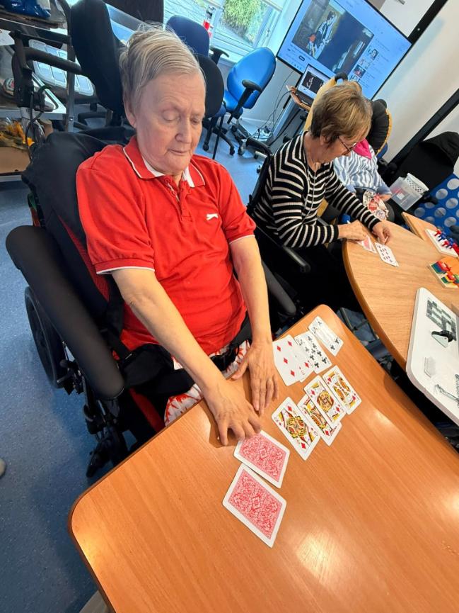resident sat in a wheelchair playing cards
