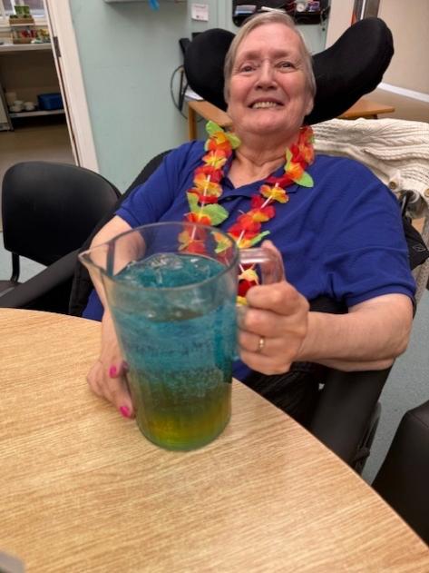 resident smiling at dee view court care home with jug of blue punch