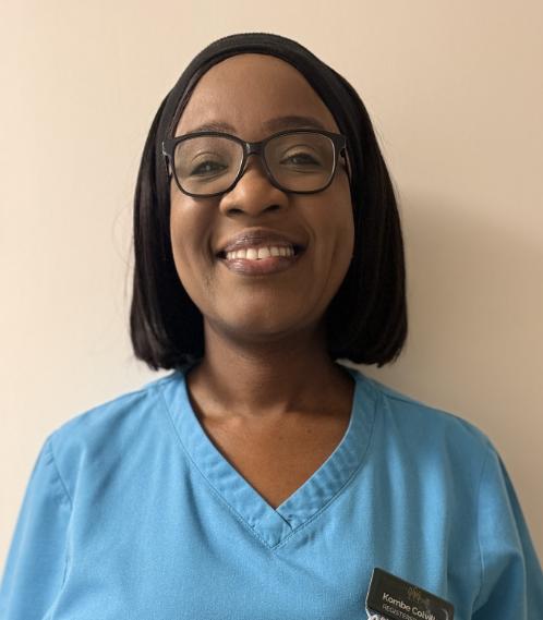 woman with glasses smiling in a light blue nurses uniform