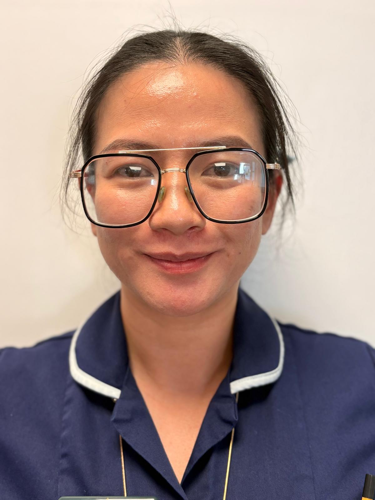 woman with large glasses in dark blue nurses uniform